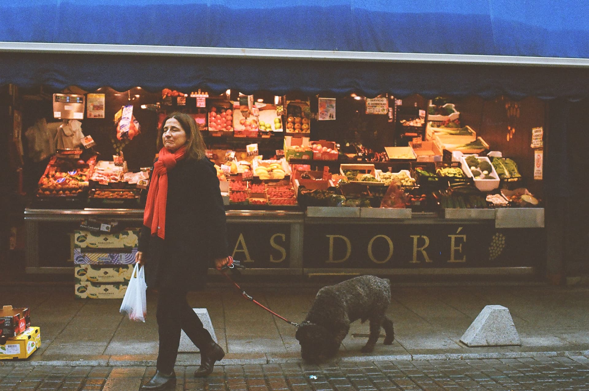 Mujer con perro frente a un puesto de mercado