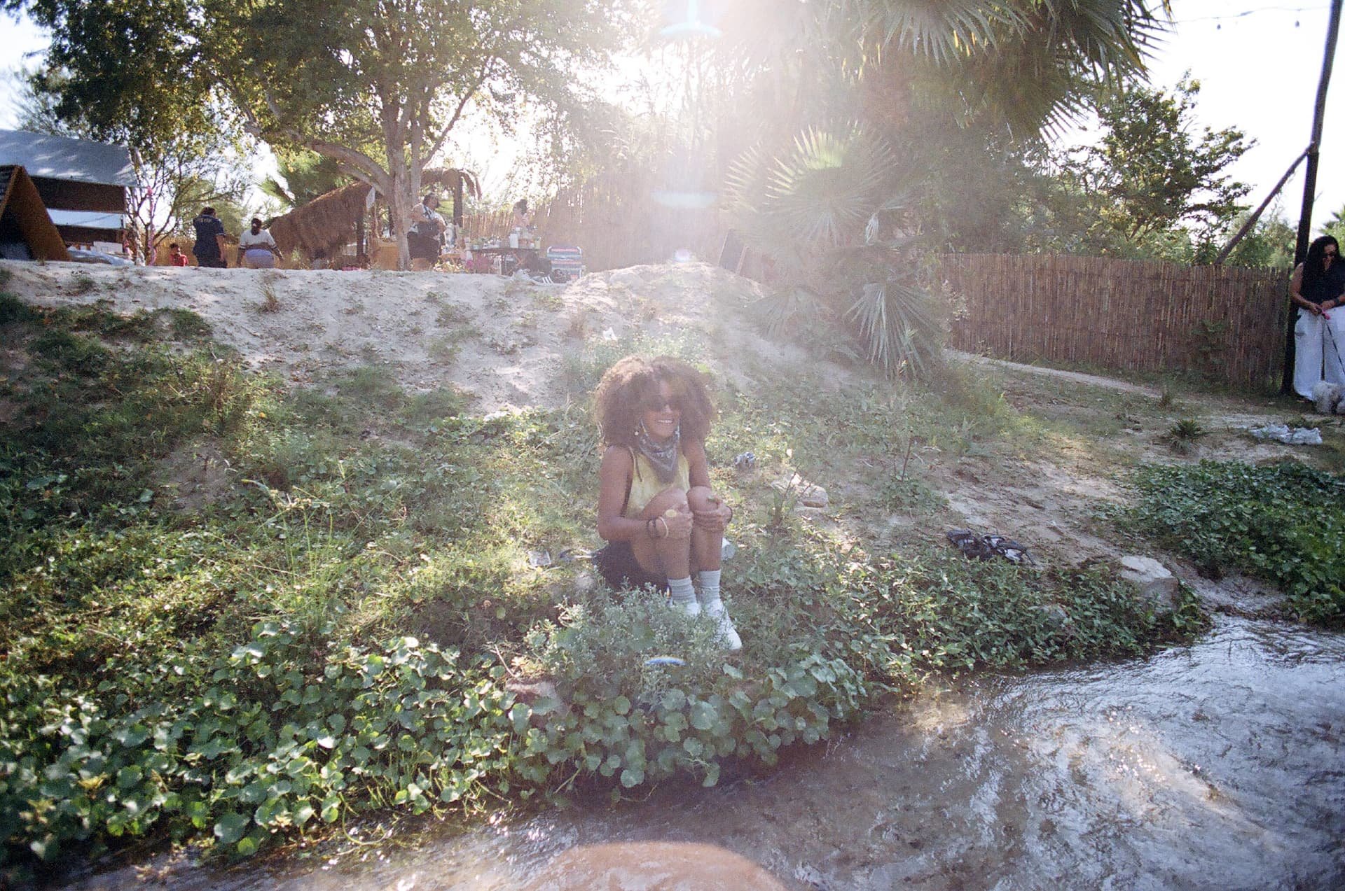 Mujer sentada junto a un arroyo entre la vegetación