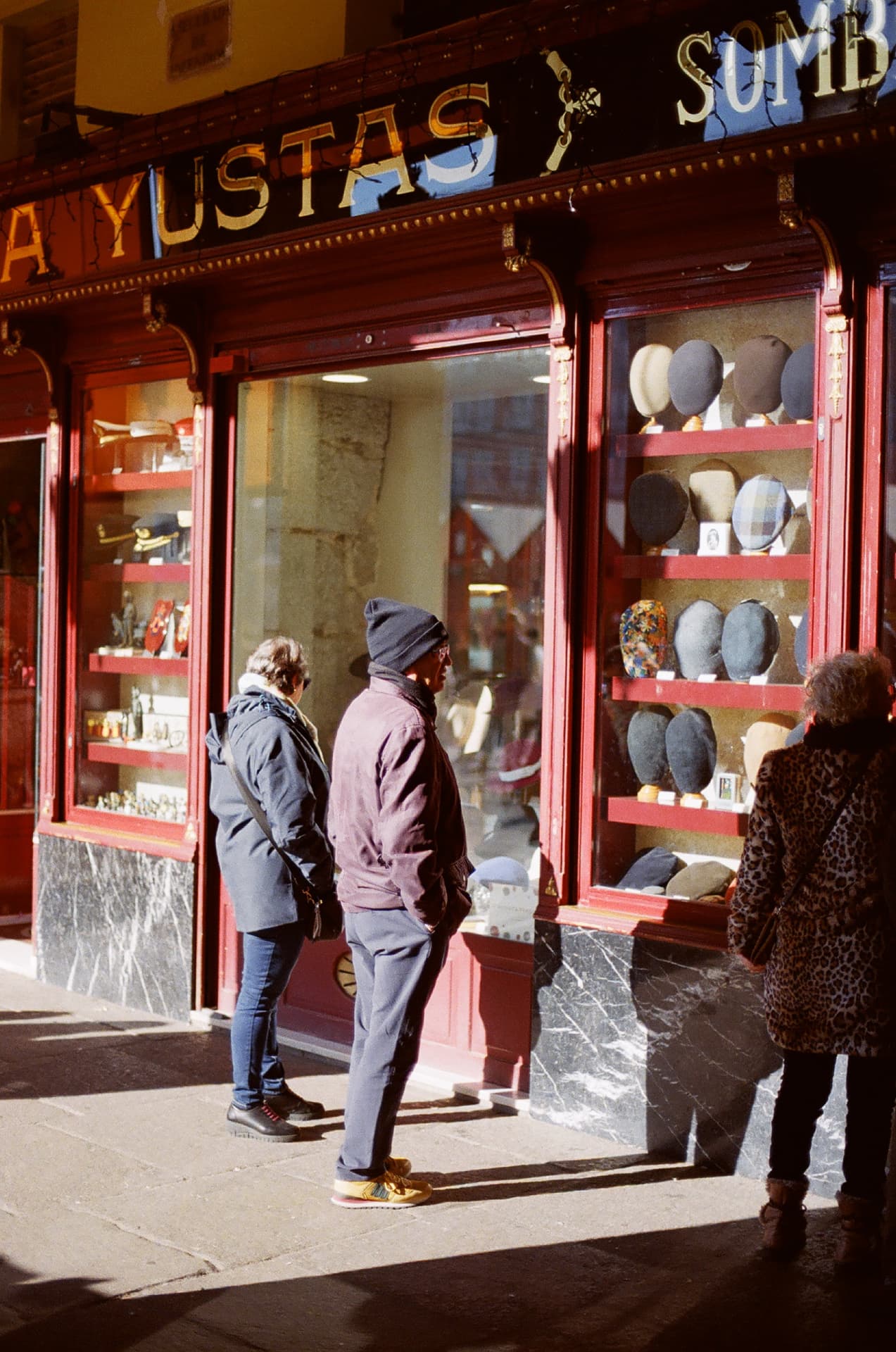 Peatones frente al escaparate de una sombrerería