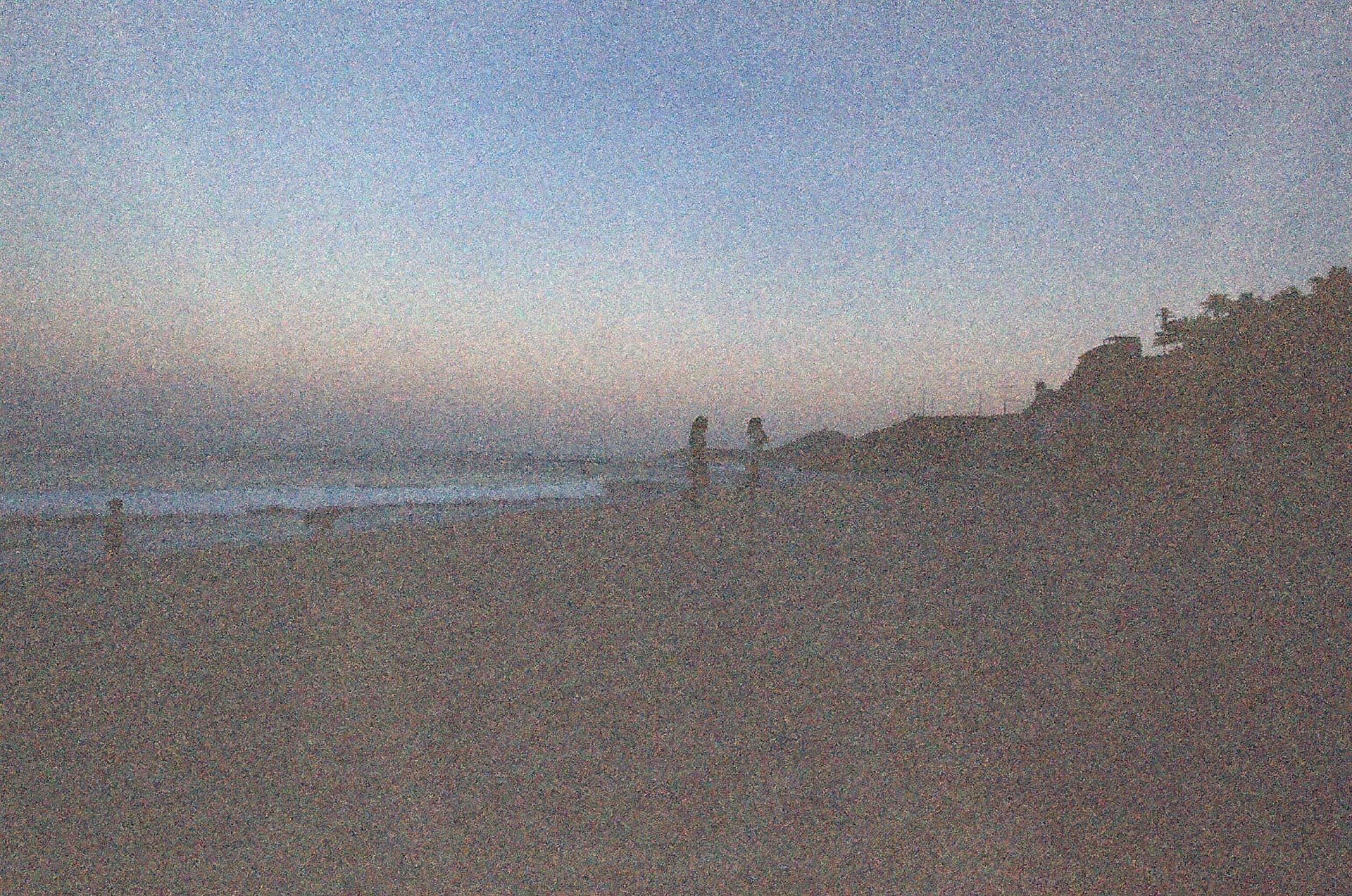 Figuras en la playa al atardecer con luz tenue