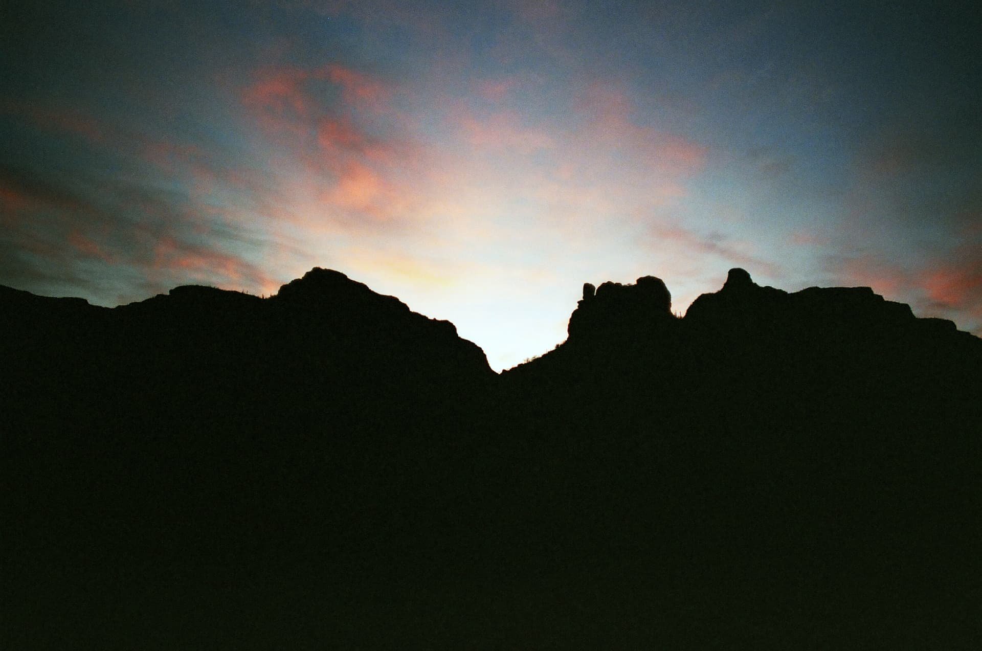 Silueta de cerros contra un cielo rosado al anochecer