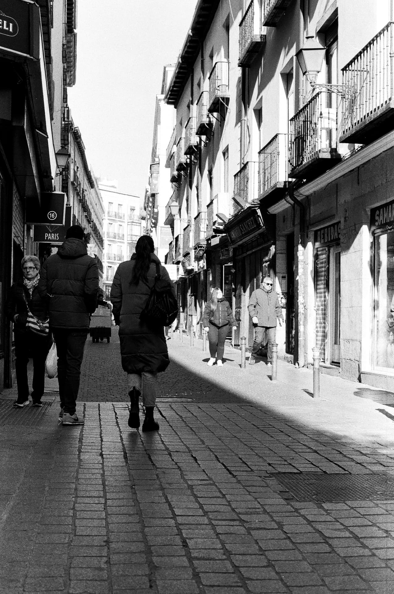 Peatones recorren una calle comercial iluminada por el sol
