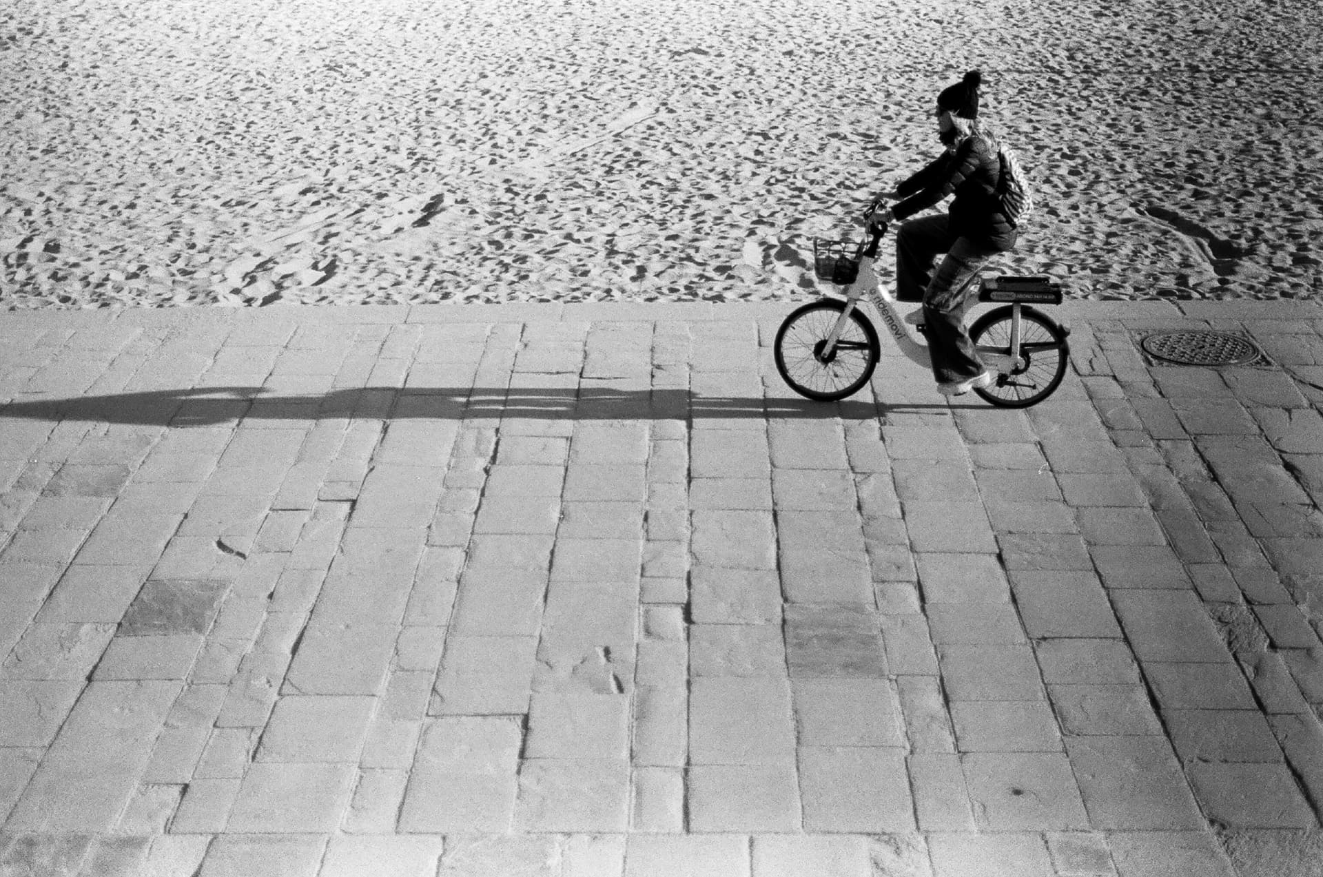 Ciclista proyecta una sombra larga junto a una plaza