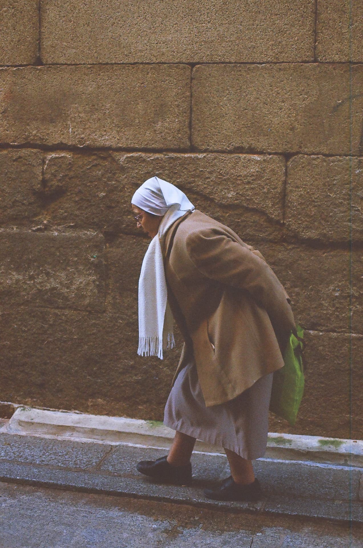 Mujer camina ante un muro de piedra
